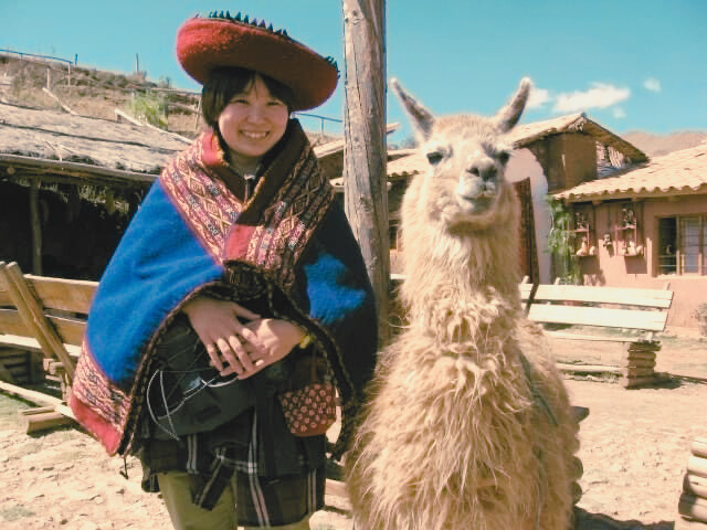 旅する よしみ助産院の院長ふじすえよしみが旅先でアルパカと 並んでいる